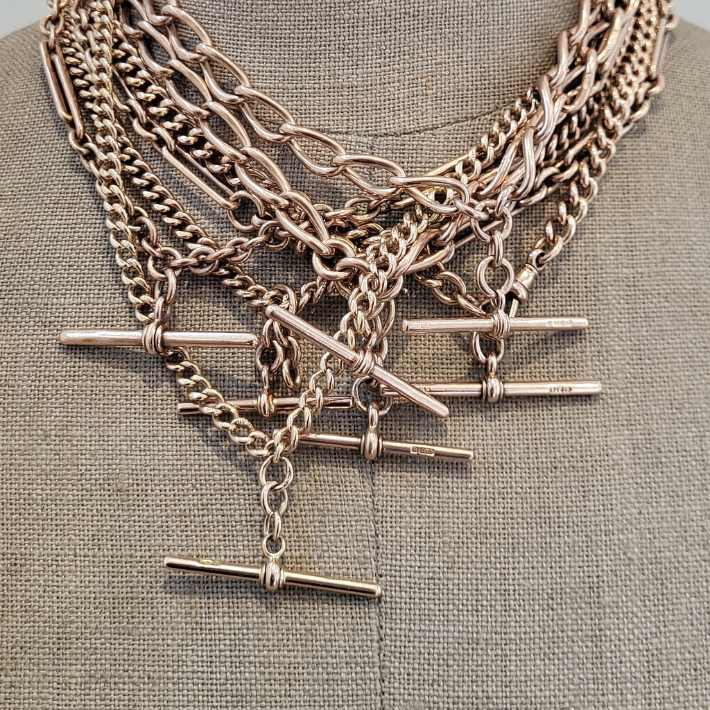 Collection of antique rose gold Albert chains draped on a mannequin