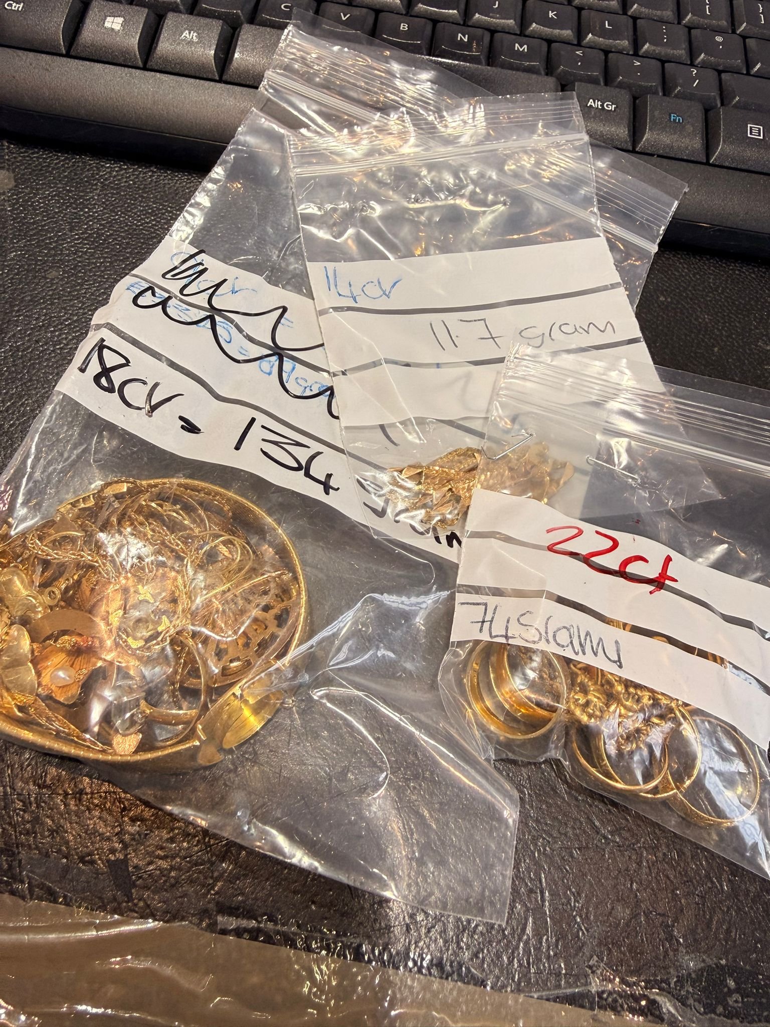 Several gold rings laid out on a dark surface showing hallmarks
